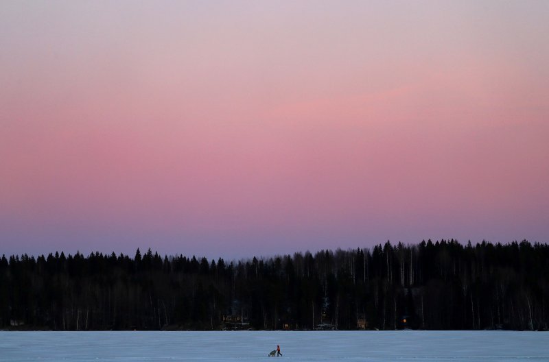 Žena gura kolica preko zaleđenog jezera u Finskoj