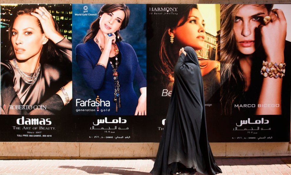 Muslimanka burka hoda pored modnih reklamnih panela