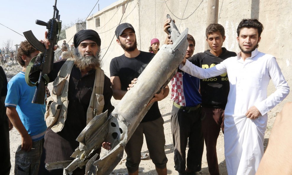 Borac Islamske države (lijevo) s lokalnim življem slavi rušenje sirijskog vojnog zrakoplova u sirijskom gradu Raqqi 