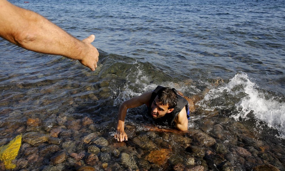 Izbjeglička kriza - Grk pomaže iscrpljenom Sirijcu koji se je domogao obale otoka Lezbosa. REUTERS - Yannis Behrakis