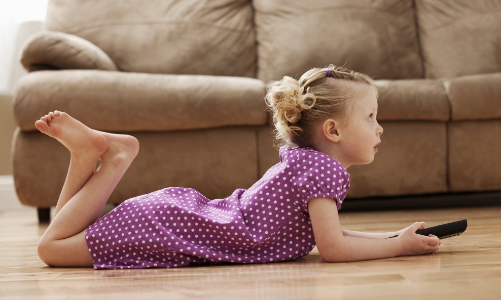 Girl (2-3) lying on floor, watching TV