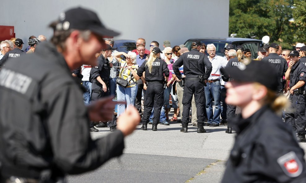 People stand outside during a visit of German Chancellor Angela Merkel to an asylum seekers accomodation facility in the eastern German town of Heidenau near Dresden, August 26, 2015 where last week more than 30 police were injured in clashes, when a mob 