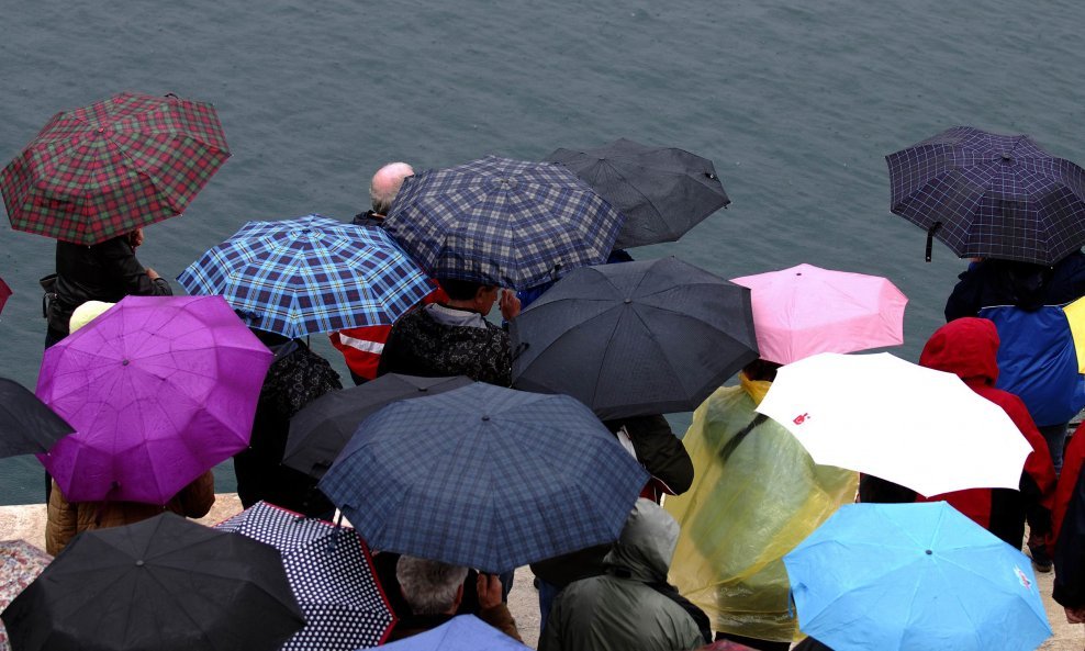 Iako pada kiša turisti koji su došli u posjet Šibeniku šetaju po staroj gradskoj jezgri ispod kišobrana.