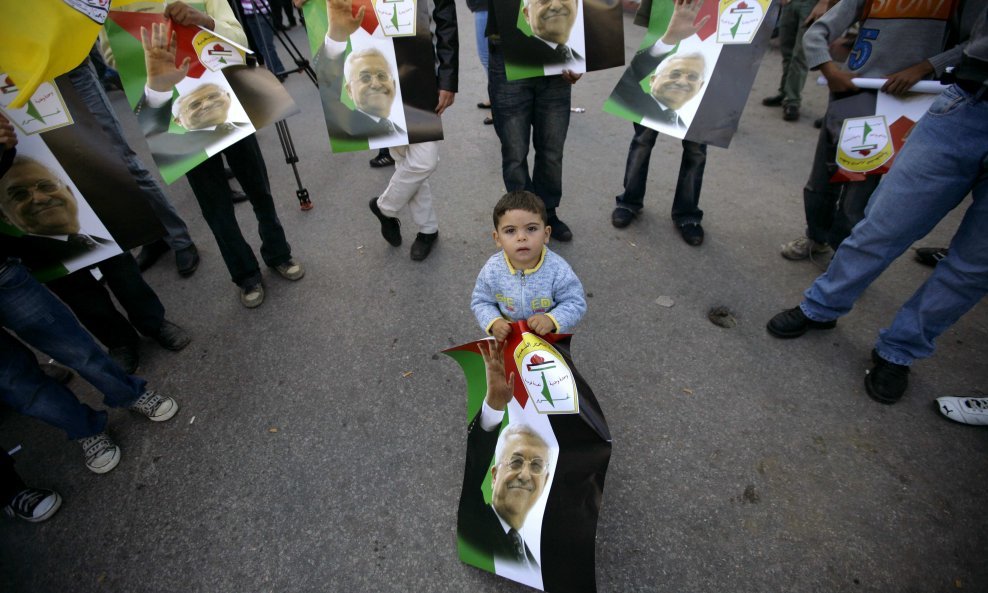 Mali Palestinac drži poster palestinskog predsjednika Mahmuda Abasa u gradu Ramali na Zapadnoj obali. Foto: REUTERS/Ammar Awad 