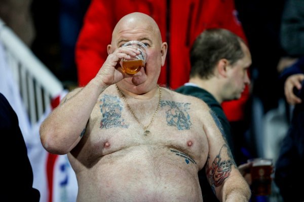 Nogometni navijač uživa u vjerojatno bezalkoholnom pivu - ilustracija
