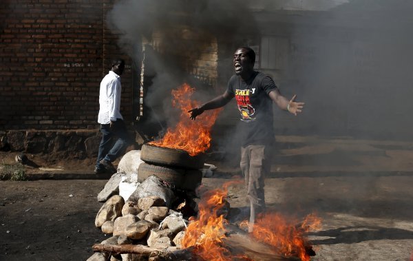 A protester, who is against President Pierre Nkurunziza's decision to run for a third term, gestures in front of a burning barricade in Bujumbura, Burundi May 14, 2015. The head of Burundi's army said on Thursday that an attempted coup had failed and forc