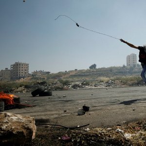 Palestinac praćkom baca kamenje na izraelske vojnike