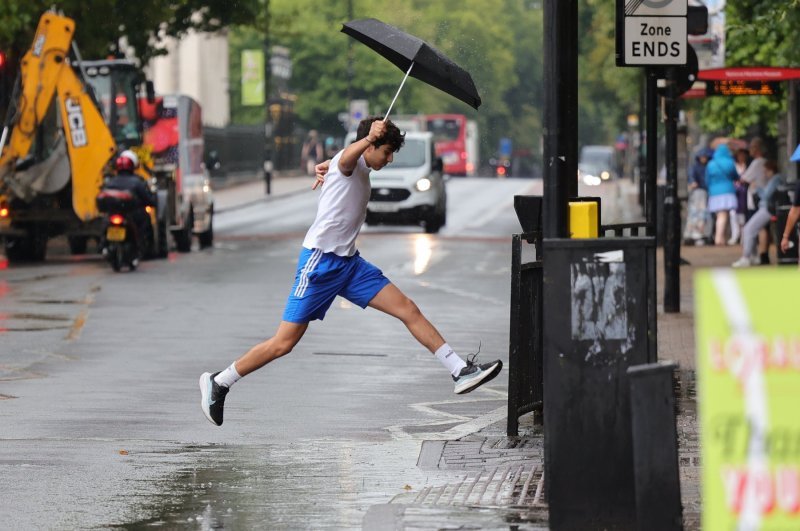 Mladić preskače lokvu vode tijekom jakih kiša u Londonu.