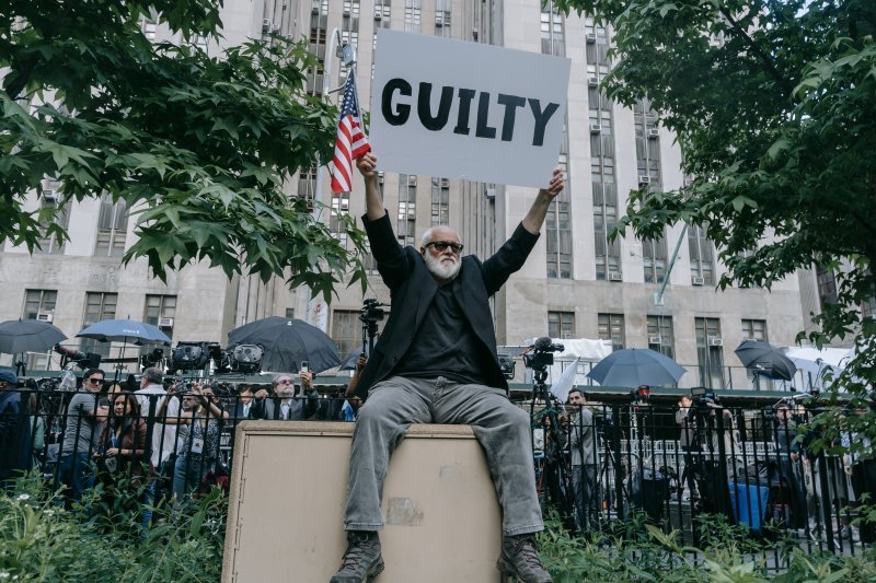 Prosvjednik nosi natpis 'Kriv je' ispred sudnice u New Yorku u kojoj je bivši američki predsjednik Donald Trump proglašen krivim zbog financijskih muljaža.
