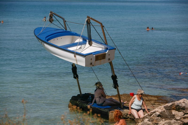 Nesmotreni turisti u potrazi za hladom na plaži stavili su svoje ručnike na poprilično opasno mjesto, pod čamac koji visi na dizalici