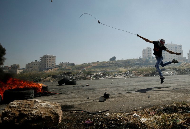 Palestinac praćkom baca kamenje na izraelske vojnike