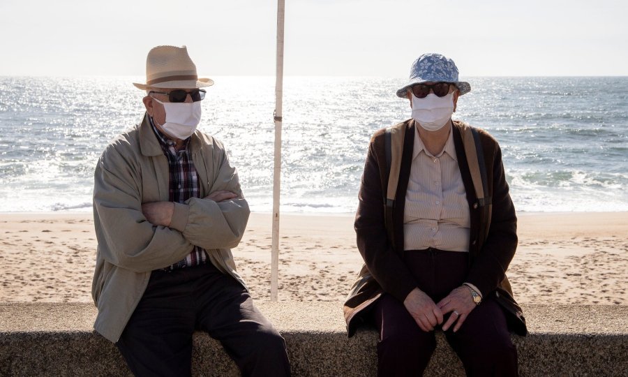 Dva starija gospodina sjede na portugalskoj plaži Espinho tijekom epidemije koronavirusa