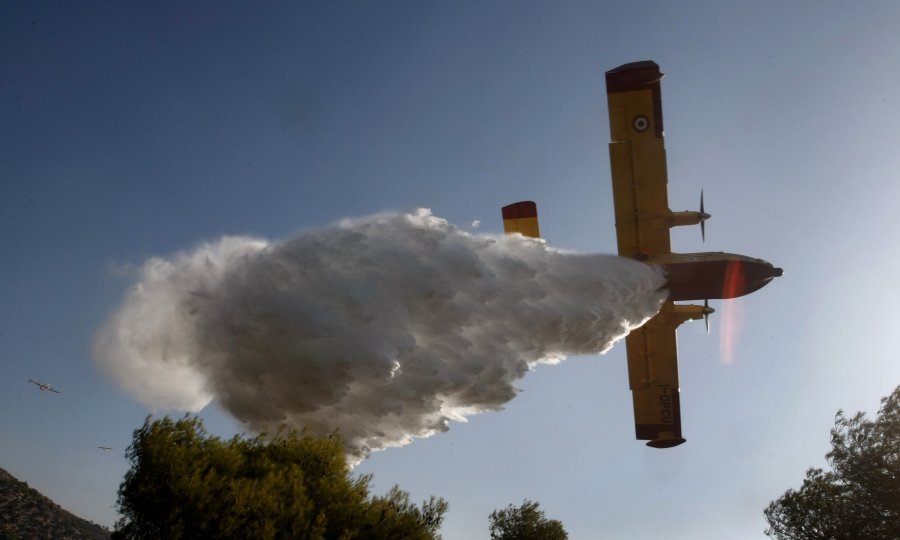 Kanader snimljen u trenutku gasilačke akcije nad šumom u grčkom selu Anatoli. Dvanaest zrakoplova i devet helikoptera pomažu stotinama vatrogasaca u gašenju požara koji su već progutali 12.000 hektara površine. Pred vatrenom stihijom iz predgrađa Atene ev