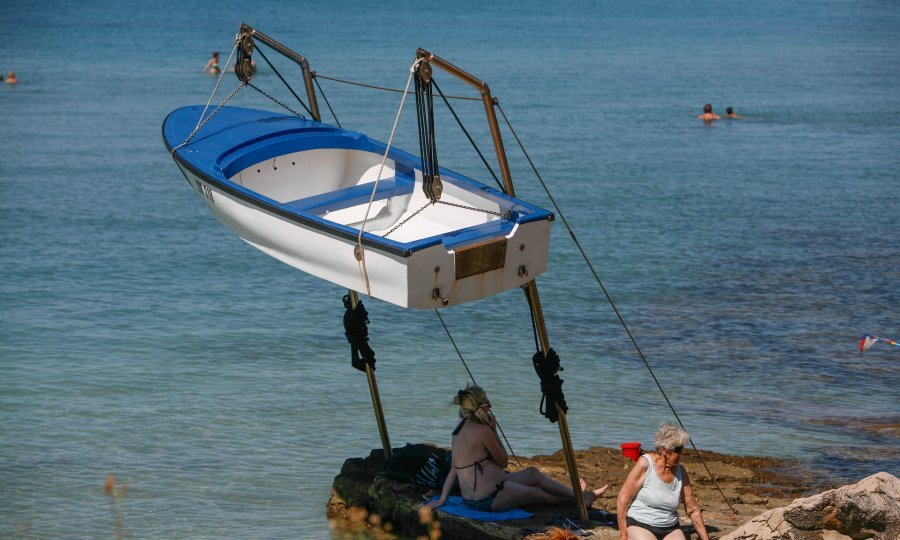 Nesmotreni turisti u potrazi za hladom na plaži stavili su svoje ručnike na poprilično opasno mjesto, pod čamac koji visi na dizalici