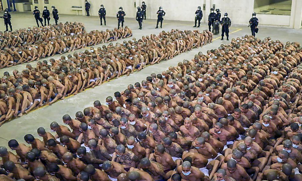 Stotine zatvorenika u kaznenom centru sjede u redovima jedan iza drugoga tako da im se dotiču lice i leđa.