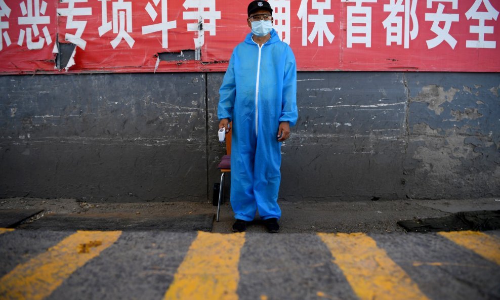 Čuvar u zaštitnom odijelu stoji na kontrolnom punktu kod pekinške veletržnice Xinfadi