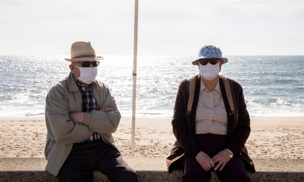 Dva starija gospodina sjede na portugalskoj plaži Espinho tijekom epidemije koronavirusa