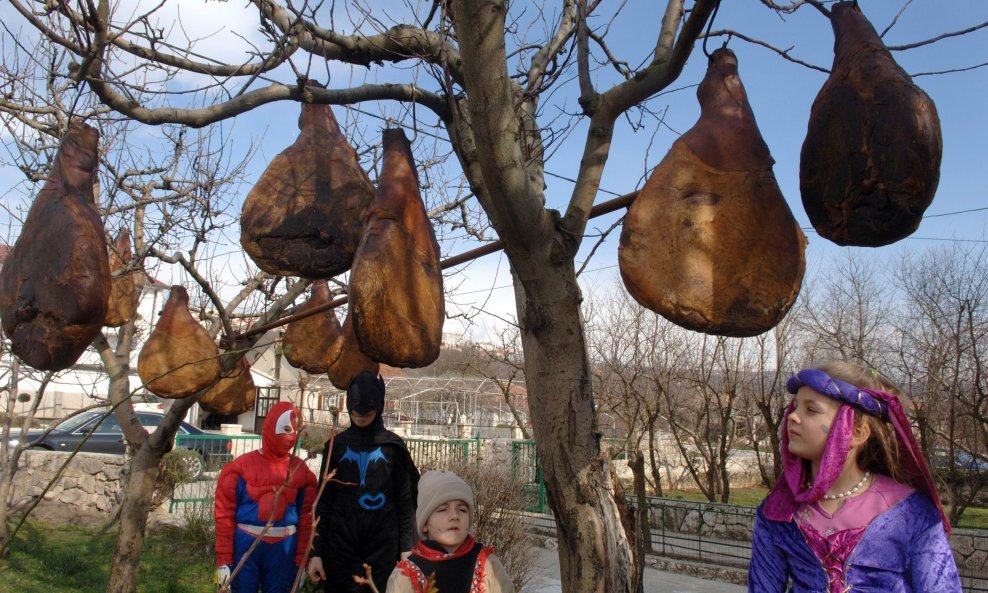 Zimska razglednica iz sela Vinjani nedaleko od Imotskog. Dok djeca obučeni u karnevalske odore prohode kroz selo vlasnik ovih pršuta objesio ih je na drvo da se suše na zimskoj buri.