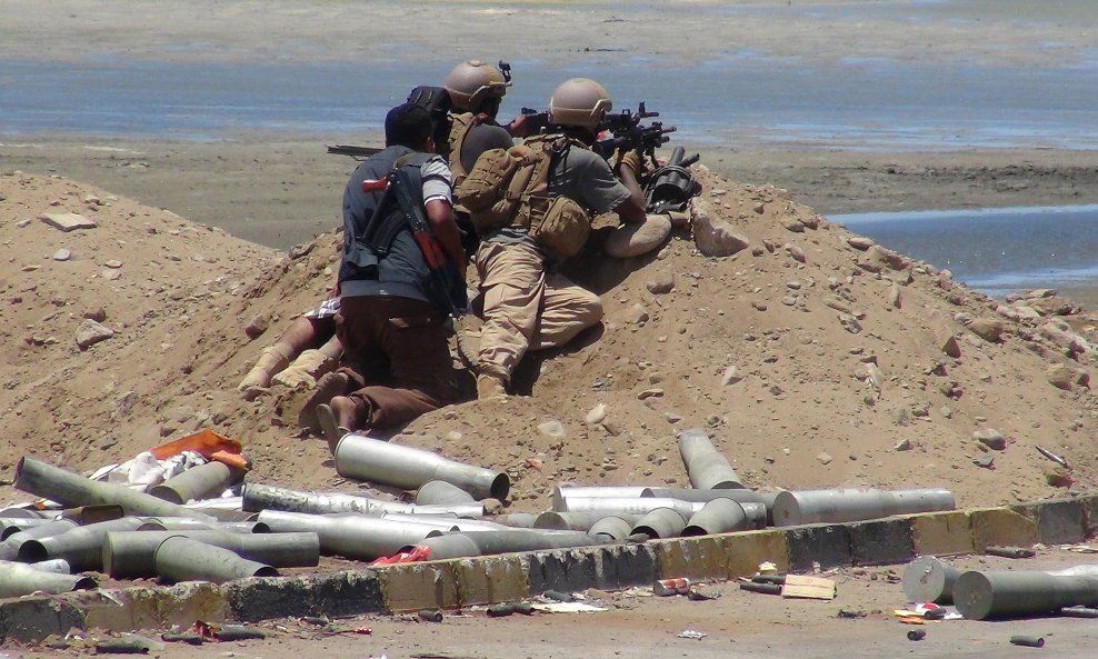 A Southern Popular Resistance fighter hides behind soldiers as they aim their weapons at Houthi positions around the airport of Yemen's southern city of Aden May 3, 2015. REUTERS/Stringer