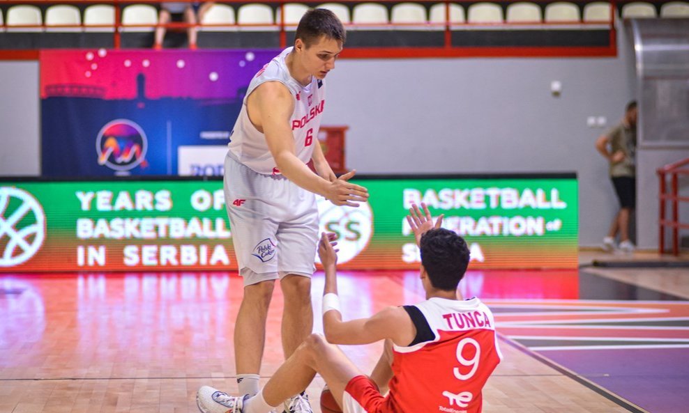 Igrač Poljske (Pawel Sowinski) pomaže vršnjaku iz Turske (Emre Tunca) da ustane nakon pada na skliskom parketu