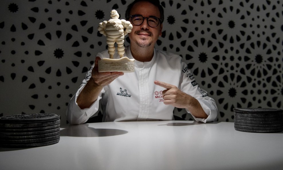 Španjolski kuhar Paco Morales drži figuricu Bibenduma, poznatog kao Michelin Man