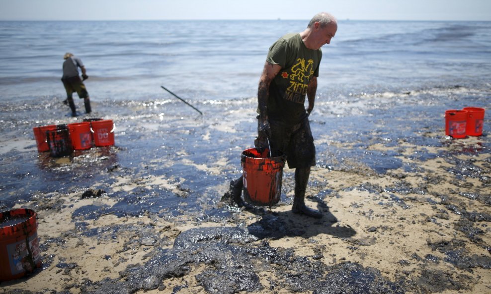  William McConnaughey, 56, (R) who drove from San Diego to volunteer, carries buckets of oil from an oil slick in bare feet along the coast of Refugio State Beach in Goleta, California, United States, May 20, 2015. A pipeline ruptured along the scenic Cal