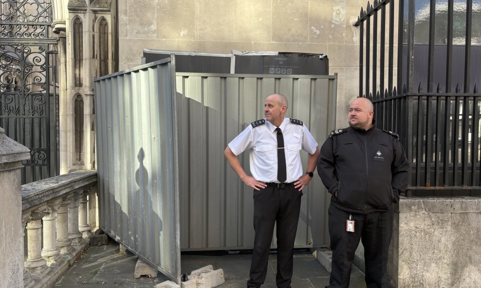 Zaštitari ispred murala prekrivenog crnom plastikom i metalnim barijerama