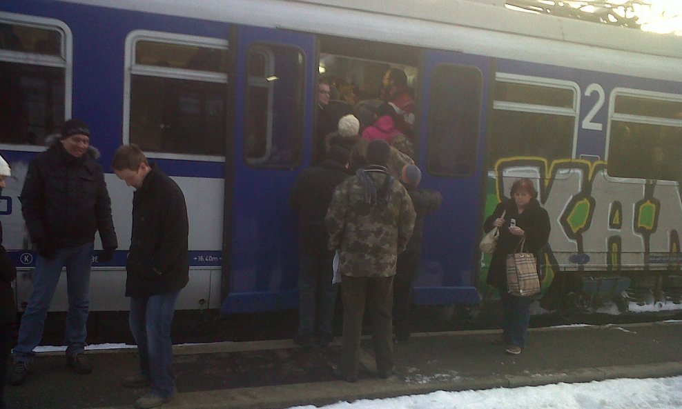 Putnici vise s vrata vlaka koji ne može krenuti