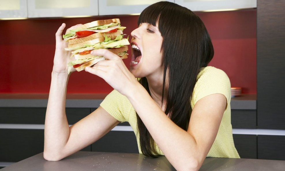 žena stavlja sendvić u usta