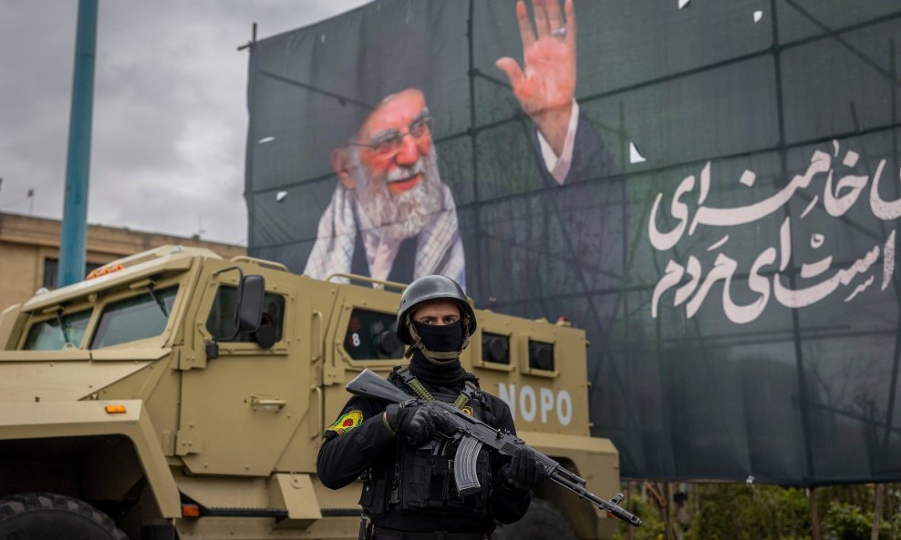 Iranska policija stoji na straži ispod portreta pokojnog iranskog vođe ajatolaha Hamneija u Teheranu - Ilustracija