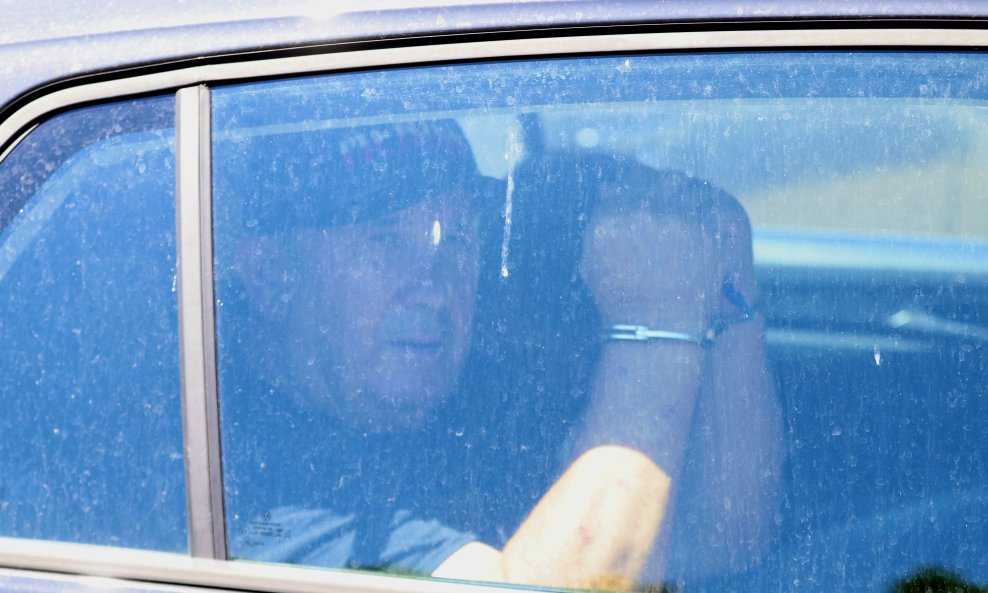 Dok je u automobilu prolazio pored fotoreportera, digao je ruke u zrak kako bi pokazao lisice, a usput se i nasmiješio