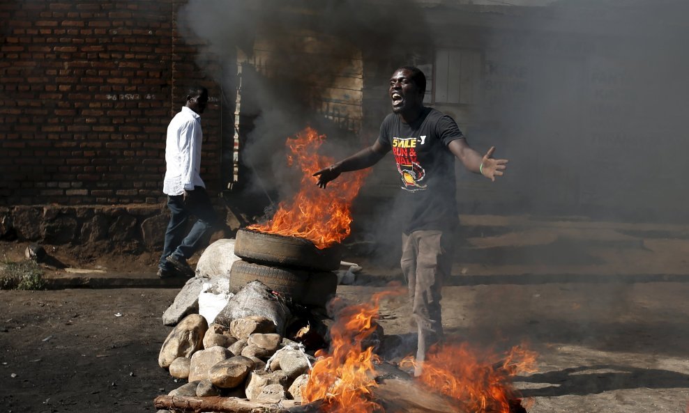 A protester, who is against President Pierre Nkurunziza's decision to run for a third term, gestures in front of a burning barricade in Bujumbura, Burundi May 14, 2015. The head of Burundi's army said on Thursday that an attempted coup had failed and forc