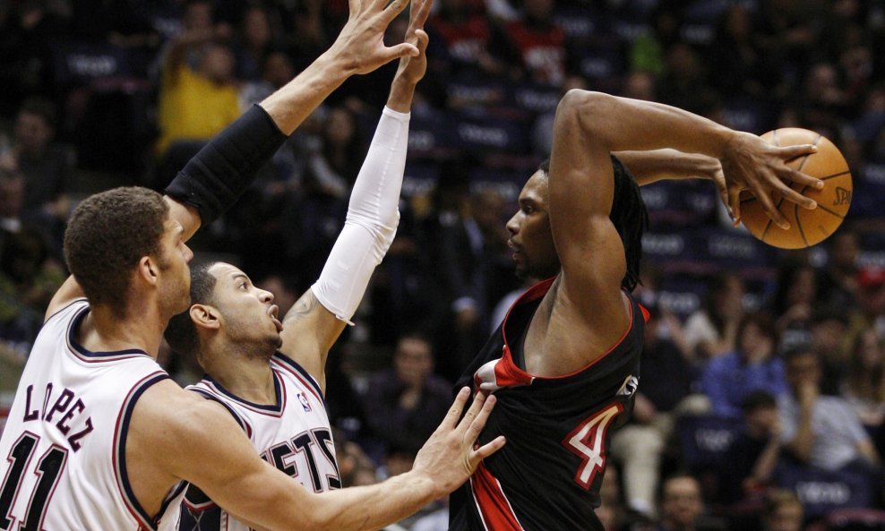 Igrači Netsa Brook Lopez i Devin Harris pokušavaju zaustaviti Chrisa Bosha