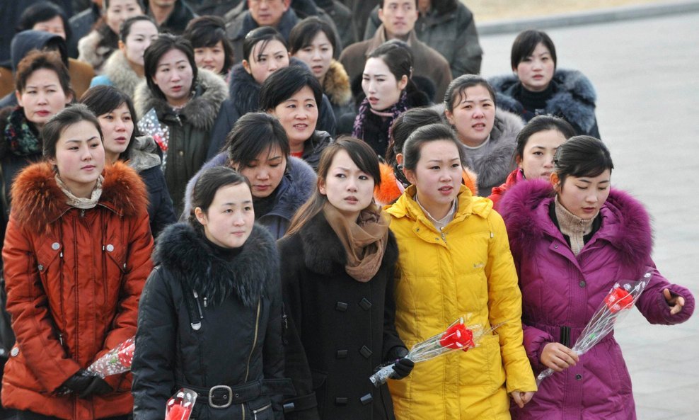 Ljudi s cvjećem u rukama dočekuju Kim Jong-ila
