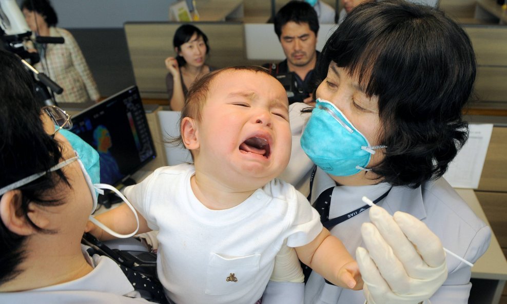 Djelatnici karantene u Južnoj Koreji pokušavaju uzeti uzorak sline bebe koja je netom sletjela iz Sjedinjenih Američkih Država na aerodrom Incheon zapadno od Seula. Dok svijetu prijeti pandemija svinjske gripe, vlade i poslovni subjekti širom svijeta naja