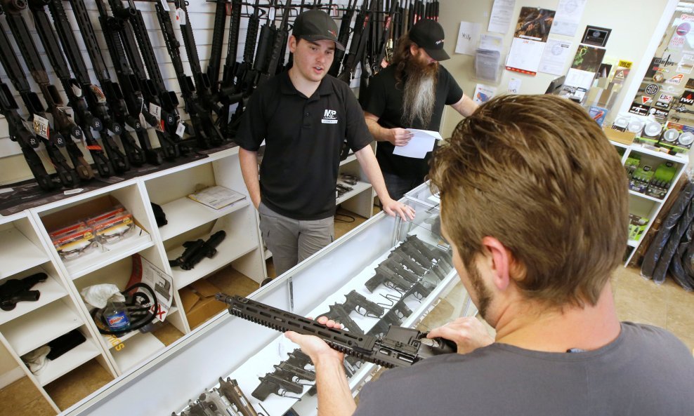 A prospective buyer examines an AR-15 as salesman Ryan Martinex watches at the "Ready Gunner" gun store in Provo, Utah, U.S., June 21, 2016. REUTERS/George Frey