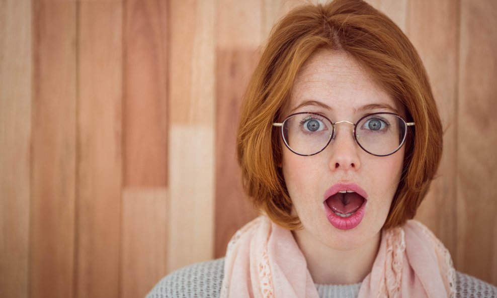 Portrait of surprised hipster woman on wooden background 