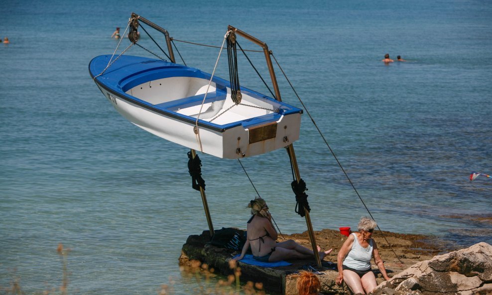 Nesmotreni turisti u potrazi za hladom na plaži stavili su svoje ručnike na poprilično opasno mjesto, pod čamac koji visi na dizalici