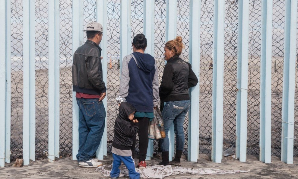 Migranti preskaču zaštitnu ogradu.
