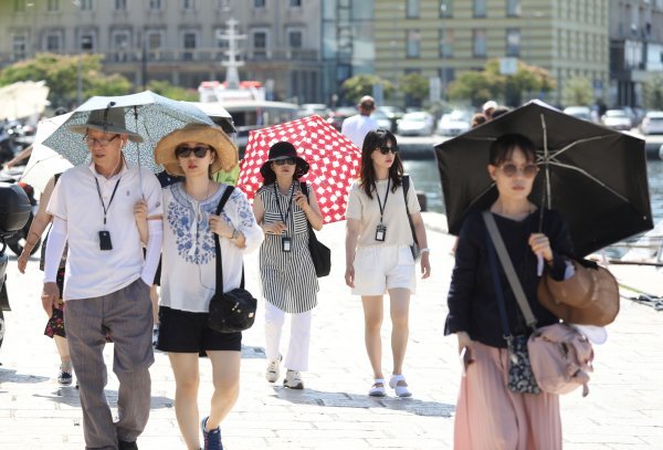 Turisti se u Šibeniku od jakog sunca štite kišobranima