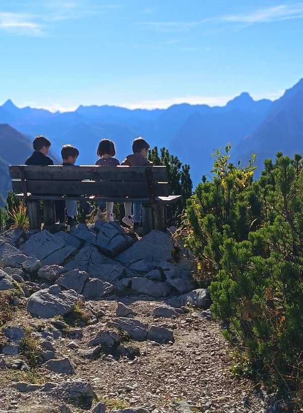 Djeca na drvenoj klupi uz planinsku stazu upijaju nestvarnu panoramu bavarskih Alpa